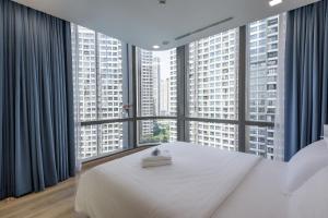 Vinhomes Central Park Apartment- Landmark Luxury في مدينة هوشي منه: غرفة نوم بسرير ابيض ونوافذ كبيرة