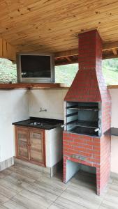 un horno de ladrillo con TV en el patio en Residência Da Família Binitz, en Visconde De Maua