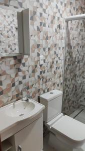 Un baño con inodoro, lavabo y espejo. en Residência Da Família Binitz, en Visconde De Maua