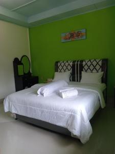 a bedroom with a large white bed with green walls at Alice Villa2 in Tuktuk Siadong