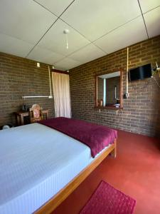 ein Schlafzimmer mit einem großen Bett und einer Ziegelwand in der Unterkunft Diduli Hotel in Ella