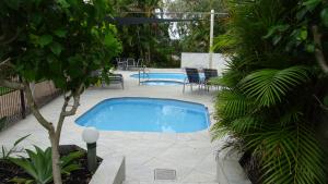a swimming pool in a yard with chairs and a tree at Noosa Gardens Riverside Resort in Noosaville