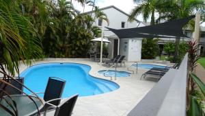 a swimming pool with chairs and an umbrella at Noosa Gardens Riverside Resort in Noosaville