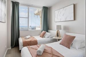 een slaapkamer met 2 bedden en een raam bij Absolute Beachfront - Panoramic Ocean Views in The Entrance
