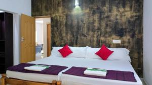 una camera da letto con un grande letto bianco con cuscini rossi di Alma Homestay a Mararikulam