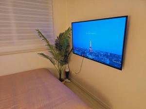 a flat screen tv hanging on a wall next to a plant at Terrace House Hwagok station in Seoul