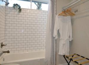 a white bathroom with a tub and a shower curtain at Hip Container APT - 5 Min Walk to TIAA Bank in Jacksonville