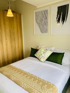 a bedroom with a bed with white sheets and green pillows at Nelly`s Green Creek Luxury Apartment in Pretoria