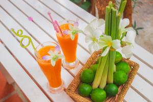a table with two glasses of juice and a basket of vegetables at Mui Ne Sunlight Villa in Mui Ne