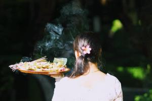 una mujer sosteniendo un plato de comida con humo en Suite Hotel Apartment Legian by RCP, en Seminyak