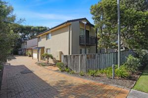 a house with a fence next to a brick driveway at Bennett's Beach House in Hawks Nest