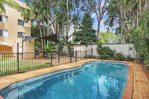 a swimming pool with a fence and trees at Bennett's Beach House in Hawks Nest