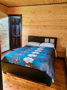 um quarto com uma cama num quarto de madeira em Cabaña El Sueño em Cartago