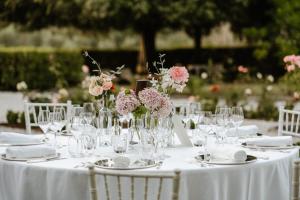 een tafel met glazen en vazen met bloemen erop bij Tenuta di Tramonte Boutique Hotel in Lucca