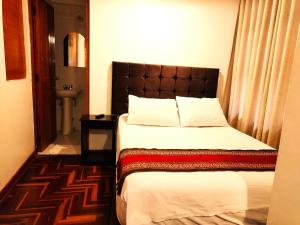 1 dormitorio con 1 cama con cabecero marrón en Paqarina San Blas, en Cusco