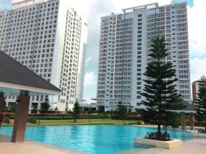 una piscina con un árbol frente a dos edificios altos en Home Of Soleil At SM Wind Tagaytay, en Tagaytay