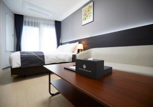 a bedroom with a bed and a desk with a laptop at Sokcho Chonpines Beach Hotel in Sokcho