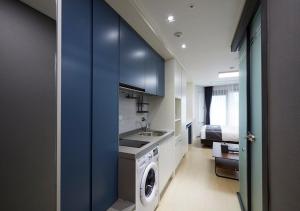 a kitchen with blue cabinets and a washer and dryer at Sokcho Chonpines Beach Hotel in Sokcho