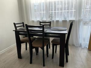 mesa de comedor negra con sillas y ventana en Апартамент Рентал 1 en Varna