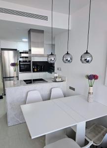 een witte keuken met een witte tafel en stoelen bij Apartment Margarita 2 in Torrevieja