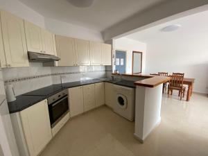 eine Küche mit weißen Schränken und einem Tisch darin in der Unterkunft Paradise Gardens 1 in Paphos City