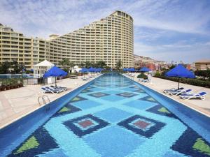 uma piscina com cadeiras e guarda-sóis azuis e um hotel em Porto Sokhna Hotel em Ain Sokhna