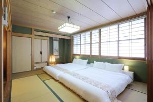 Cette chambre comprend un grand lit blanc et des fenêtres. dans l'établissement bHOTEL Kaniwasou 301 Minute walk from Miyajima Pier for 11ppl, à Miyajima