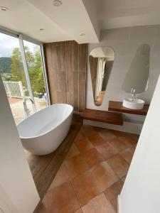 een badkamer met een groot wit bad en een wastafel bij Villa Indigo in Le Carbet