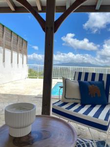 eine Terrasse mit einem Stuhl, einem Tisch und einem Tisch in der Unterkunft Villa Indigo in Le Carbet