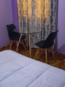 a bedroom with a glass table and two chairs at Casa Hotel Místico in Ayacucho