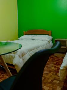 a green room with a bed with a glass table at Casa Hotel Místico in Ayacucho