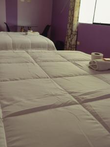 a group of three white beds in a room at Casa Hotel Místico in Ayacucho
