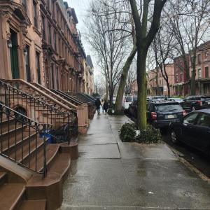 a sidewalk with cars parked on a city street at New York City GuestHouse in New York