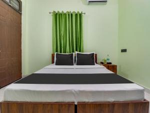 a bedroom with a large bed with a green curtain at OYO Shri Radhe Guest House & Restaurant in Rishīkesh