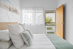 a bedroom with a bed with white pillows and a window at Chic 2-Bed Cabin-Style Home by Mooloolaba Beach in Mooloolaba