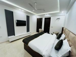 a bedroom with a bed and a flat screen tv at Hotel Royal Oakes - East of Kailash in New Delhi