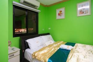 a bedroom with green walls and a bed with two pillows at Golden V Primera Unit B in Malolos