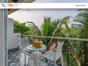 a table and chairs on a balcony with palm trees at Beach Doorz Place-TBV in Baga