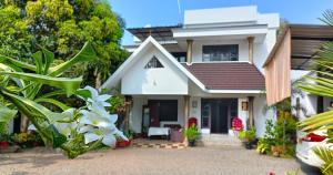 a white house with a white flower in front of it at Alma Homestay in Mararikulam