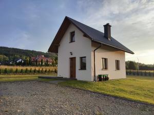 a small white house with a black roof at Domek pod Żukowem in Ustrzyki Dolne