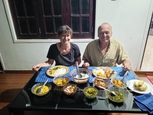 波隆納魯沃的住宿－Deer Garden Guest，坐在餐桌旁吃饭的男人和女人