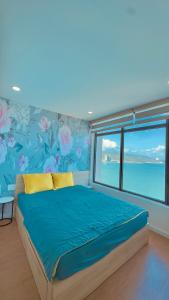 a bedroom with a blue bed with a window at Oceanus Oasis Retreat Muong Thanh Vien Trieu in Nha Trang