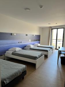 Habitación con 3 camas y ventana en CIS Lamourelle Centre International de Sejour, en Carcassonne