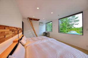 um quarto com uma cama e 2 janelas grandes em Altitude -アルティチュード-939 富士山の麓グランピング em Fujiyoshida