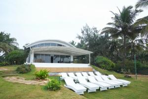 a group of white chairs in front of a building at Beach House Resort Goa in Benaulim