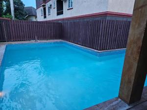 a swimming pool with blue water in front of a fence at Paradise Haven at Hamptons - -across from Ac Marriot Hotel in Kingston