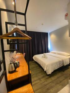 um quarto de hotel com uma cama e uma mesa com uma chaleira. em Super 8 Hotel Alor Setar em Alor Setar