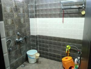 a bathroom with a tiled shower with a bucket at Kshitijshomestay in Lucknow