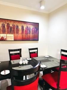 a dining room with a black table and red chairs at Mafumu Hotel in Lilongwe