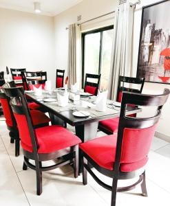 a dining room with a table and red chairs at Mafumu Hotel in Lilongwe